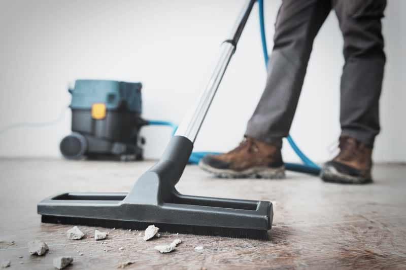 Post-construction cleanup with vacuum and debris removal from unfinished floor